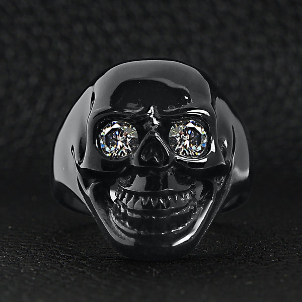 Stainless steel clear Cubic Zirconia eyed black skull ring on a black leather background.