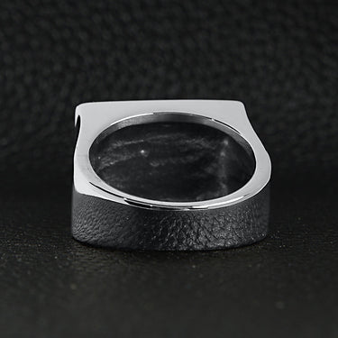 Stainless steel motorcycle club "MC" insignia signet ring back view on a black leather background.