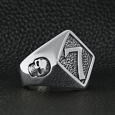 Stainless steel lucky "7" with skull accents signet ring on a black leather background.