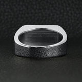 Stainless steel motorcycle club "MC" insignia signet ring back view on a black leather background.