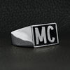 Stainless steel motorcycle club "MC" insignia signet ring angled on a black leather background.