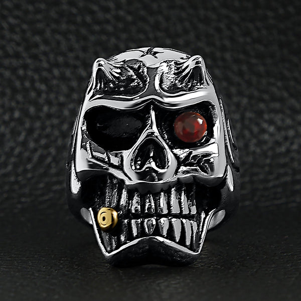 Stainless steel devil skull with red Cubic Zirconia eye smoking 18K gold PVD Coated cigar ring on a black leather background.