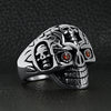 Stainless steel red Cubic Zirconia eyed sugar skull ring angled on a black leather background.