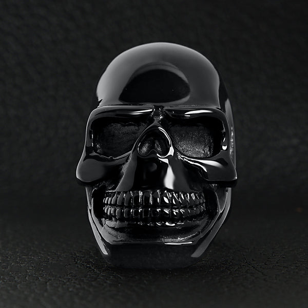 Stainless steel black skull ring on a black leather background.