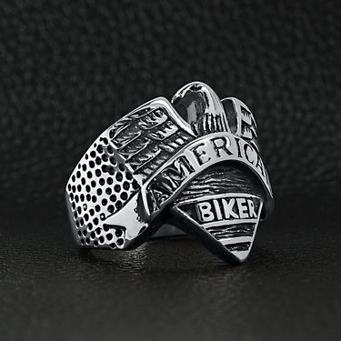 Stainless steel "AMERICAN BIKER" with eagle ring angled on a black leather background.
