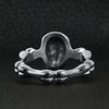 Stainless steel skull and bones women's ring back view on a black leather background.