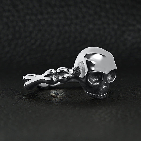 Stainless steel skull and bones women's ring angled on a black leather background.
