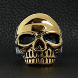 Stainless steel and 18K gold PVD Coated skull ring on a black leather background.