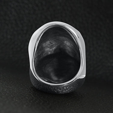 Stainless steel USA American flag covered skull ring back view on a black leather background.