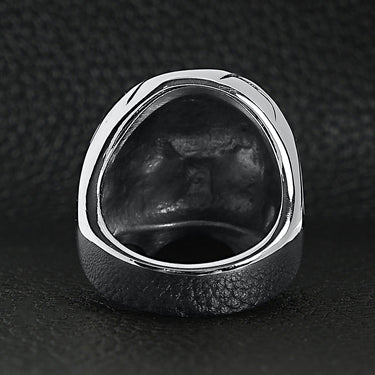 Stainless steel blue Cubic Zirconia eyed cracked skull ring back view on a black leather background.