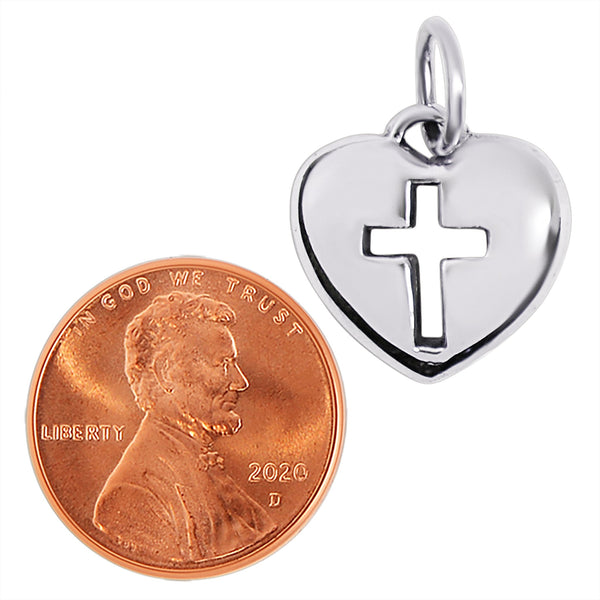 Sterling silver heart cross cutout pendant with a penny for scale.