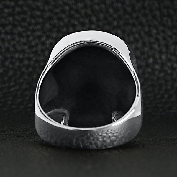 Sterling silver skull ring back view on a black leather background.