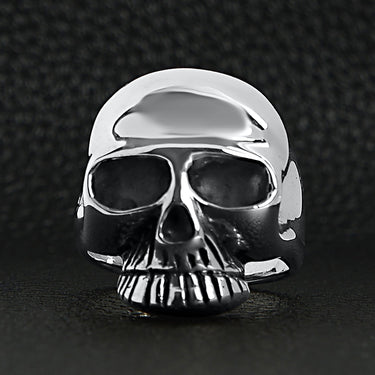 Sterling silver skull ring on a black leather background.