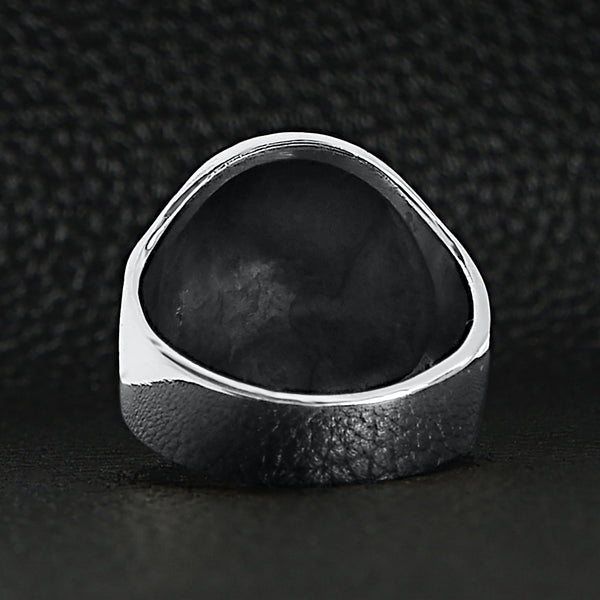 Sterling silver black eyed skull ring back view on a black leather background.