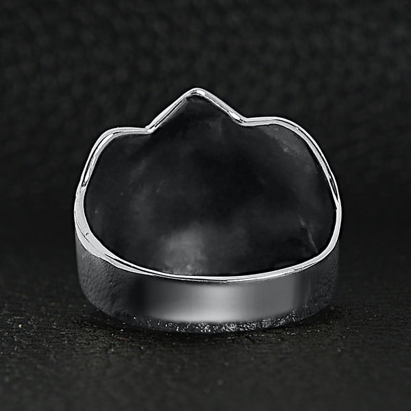 Sterling silver winged skull and crossbones shield ring back view on a black leather background.