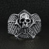 Sterling silver winged skull and crossbones shield ring on a black leather background.