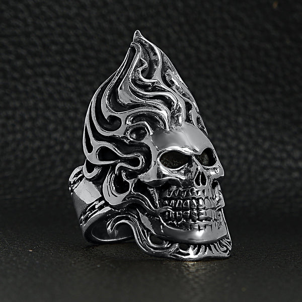 Sterling silver flaming skull with chain accents ring at an angle on a black leather background.