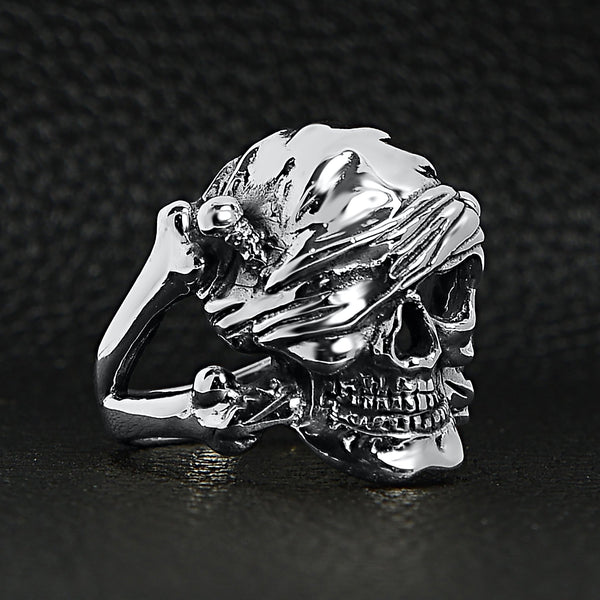 Sterling silver pirate skull ring angled on a black leather background.