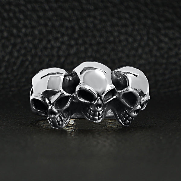 Sterling silver triple back eyed skulls ring on a black leather background.