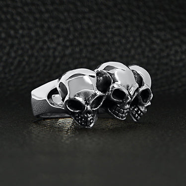 Sterling silver triple back eyed skulls ring at an angle on a black leather background.