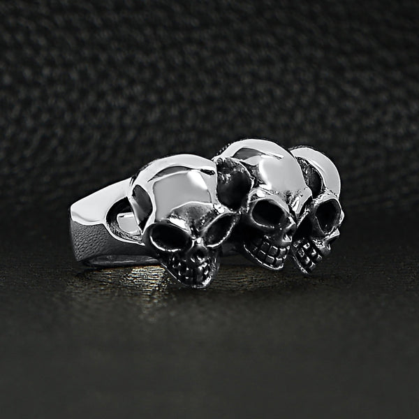 Sterling silver triple back eyed skulls ring at an angle on a black leather background.