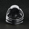 Sterling silver screaming cracked skull with bones ring back view on a black leather background.