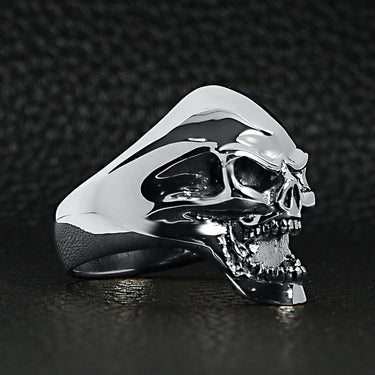 Sterling silver screaming skull ring angled on a black leather background.