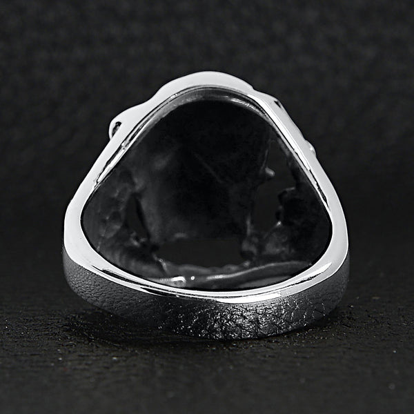 Sterling silver skull tearing through ring back view on a black leather background.