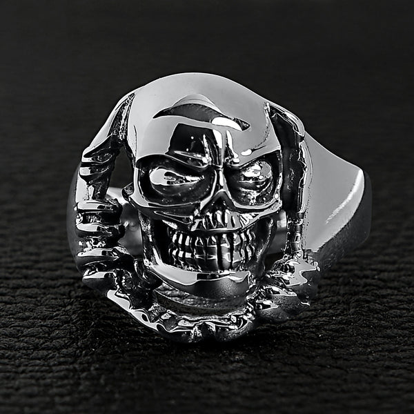Sterling silver skull tearing through ring on a black leather background.