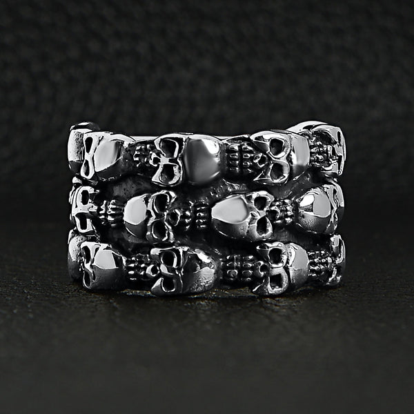 Sterling silver triple layer skulls ring on a black leather background.