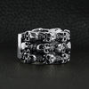 Sterling silver triple layer skulls ring angled view on a black leather background.