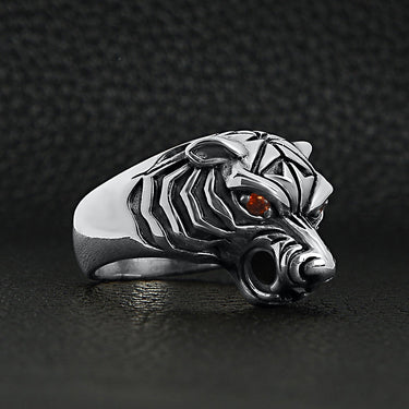 Sterling silver red Cubic Zirconia eyed tiger ring angled on a black leather background.