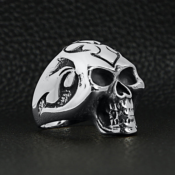 Sterling silver flaming skull ring angled on a black leather background.