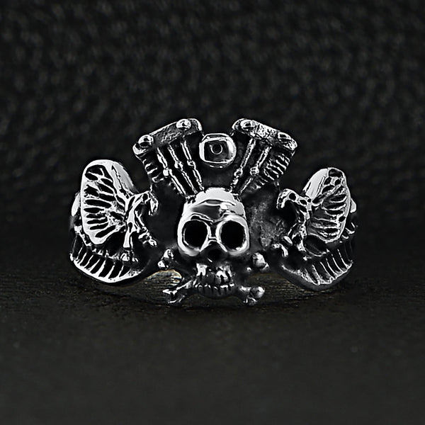 Sterling silver winged skull and crossbones eagle engine ring on a black leather background.