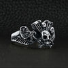 Sterling silver winged skull and crossbones eagle engine ring angled on a black leather background.