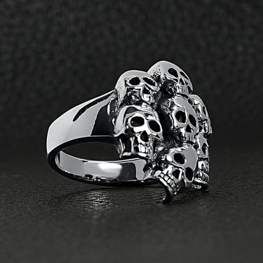 Sterling silver skull pile ring at an angle on a black leather background.