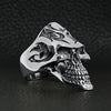 Sterling silver flaming skull ring at an angle on a black leather background.