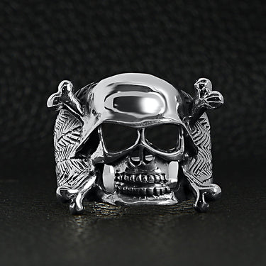 Sterling silver helmet skull and crossbones ring on a black leather background.