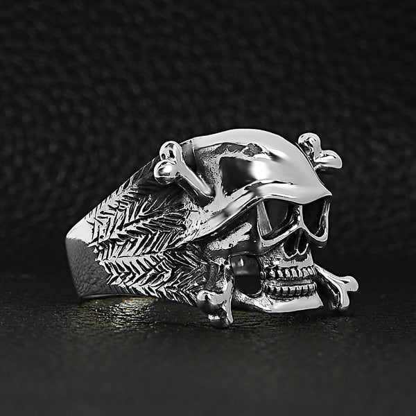 Sterling silver helmet skull and crossbones ring at an angle on a black leather background.