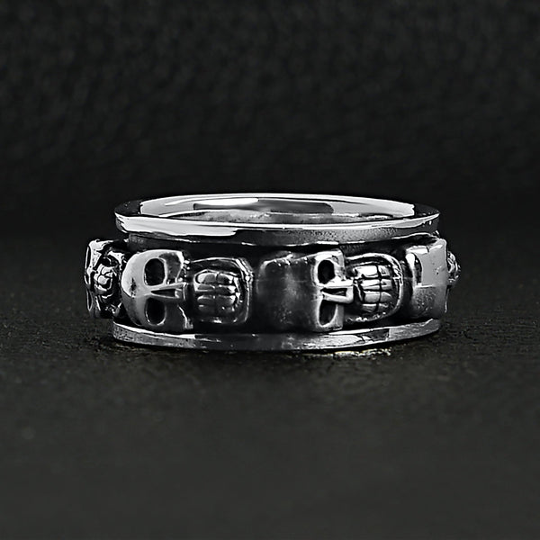 Sterling silver skull spinner ring on a black leather background.