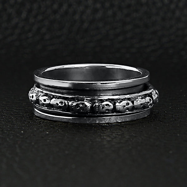 Sterling silver skull spinner ring on a black leather background.