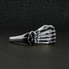 Sterling silver skeleton hand ring at an angle on a black leather background.