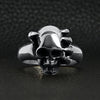 Sterling silver skull in demon hand ring on a black leather background.