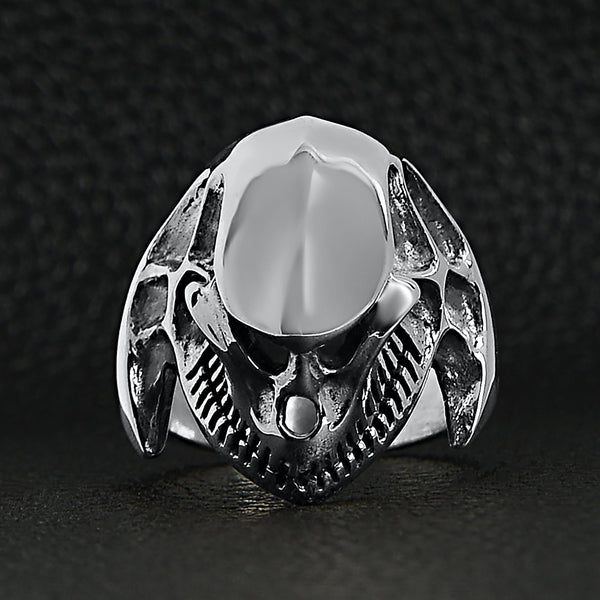 Sterling silver alien skull ring on a black leather background.