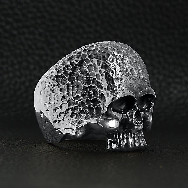 Sterling silver hammered texture skull ring at an angle on a black leather background.