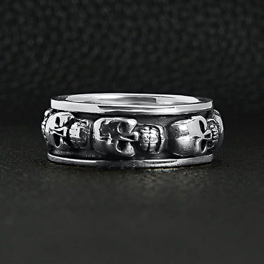 Sterling silver skull spinner ring on a black leather background.