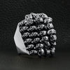 Sterling silver stacked skulls ring angled on a black leather background.