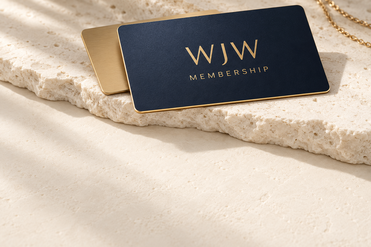 Premium navy WJW membership card with gold lettering and a champagne card on ivory stone